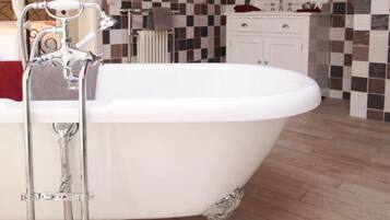 Un baño con una bañera independiente, un lavabo blanco y un salpicadero de azulejos.