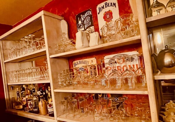 A bar with shelves stocked with various bottles and glasses. - Comme à la ferme (Durbuy)