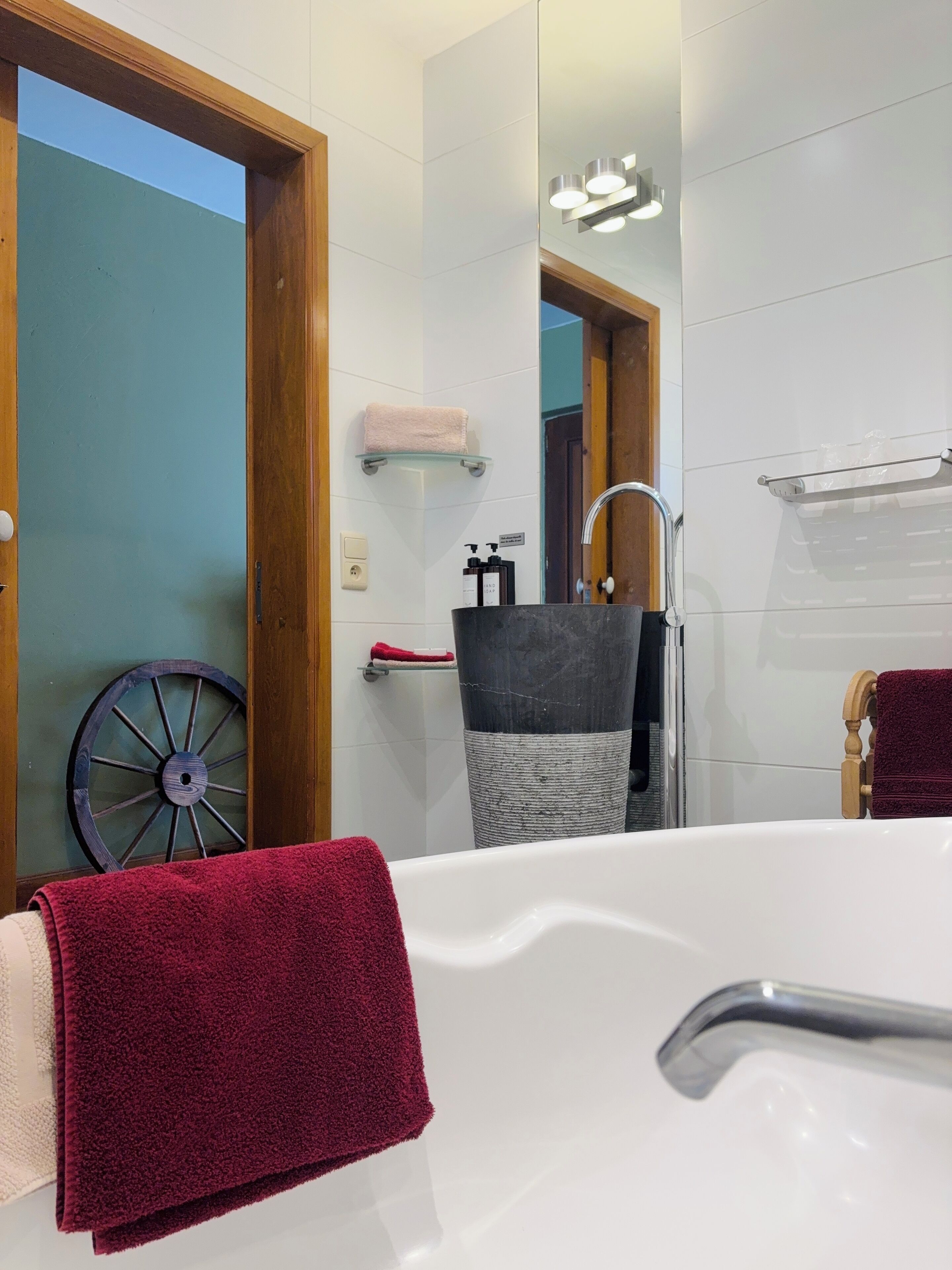 Une salle de bain avec une baignoire, une porte en bois, un miroir et un porte-serviettes.