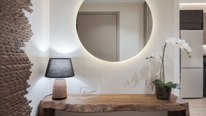 Una mesa de madera con una lámpara y un letrero, un espejo redondo y una orquídea en maceta.