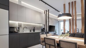Una cocina moderna con armarios oscuros, una mesa de comedor de madera y una lámpara colgante.