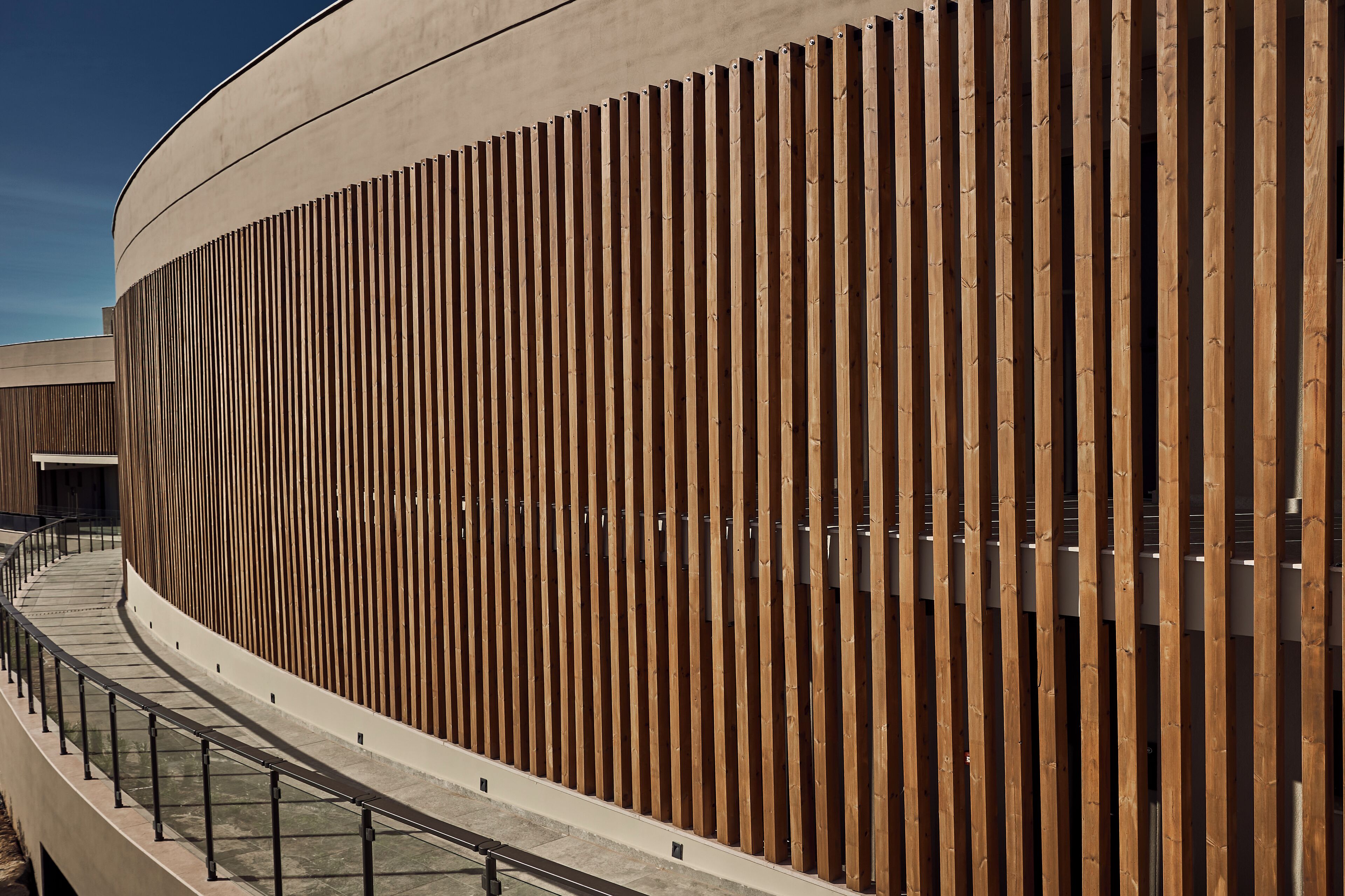 A modern building with a curved facade and vertical wooden slats.
