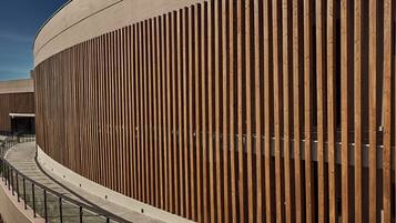 A modern building with a curved facade and vertical wooden slats.