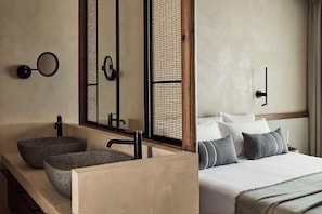 Un baño moderno con un lavamanos de piedra, un espejo y un mueble de tocador de madera.