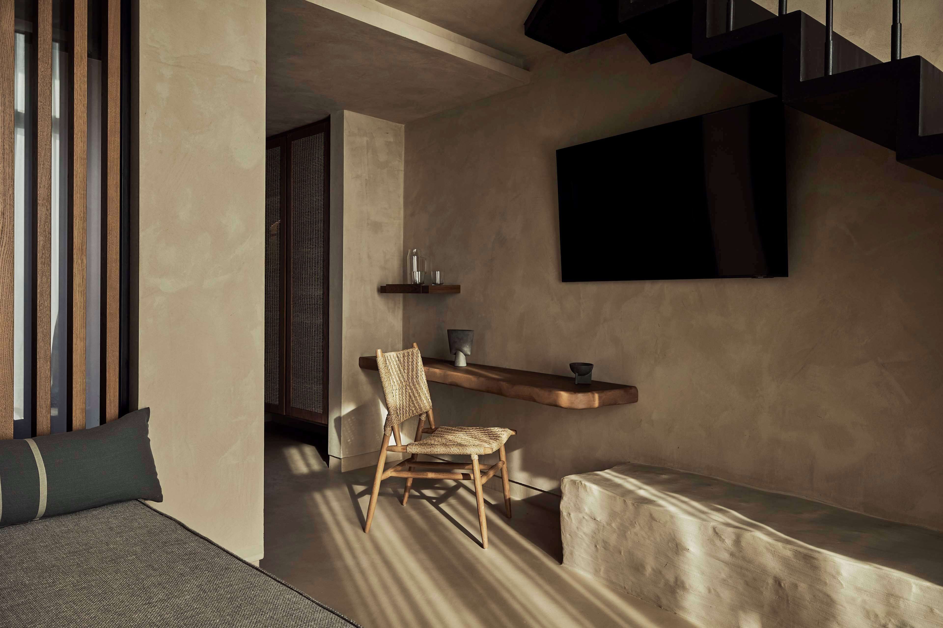Un interior moderno con una silla de madera, un banco, un estante con adornos y una escalera.