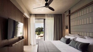 A modern bedroom with a large bed, a flat-screen TV, a ceiling fan, and a view of the outdoors. - Zélia Halkidiki, part of Destination by Hyatt - Adults Only (Nea Propontida)
