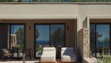 A modern hotel with a pool, outdoor seating, and large windows.