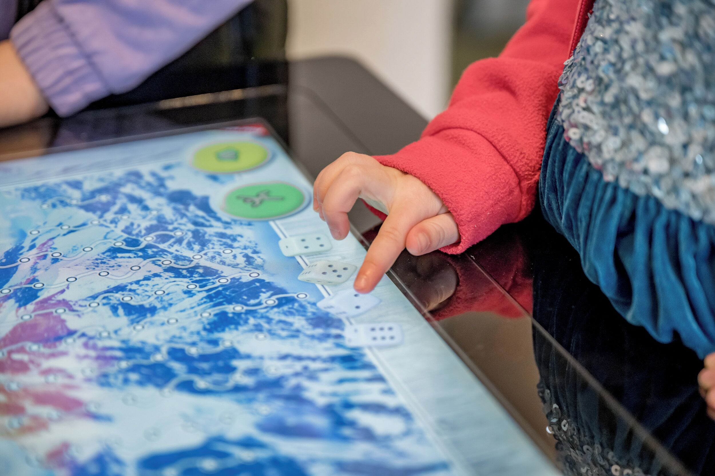 Uma criança interage com um mapa digital sobre uma mesa.