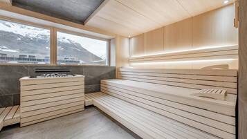 A modern sauna with wooden benches and a control panel, large windows with a mountain view, and a sleek, minimalist design.