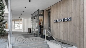 A reception area with a wooden wall, a staircase leading inside, and a glass door. - GREEN.Apartments by Camping Sölden (Soelden)