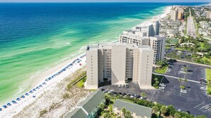 A coastal hotel with a beach view, parking, and a road leading to the beach.