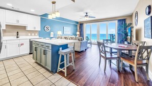 Una cocina moderna con una isla central, un comedor con mesa redonda y un balcón con vistas.