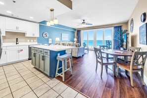 Una cocina moderna con una isla central, un comedor con mesa redonda y un balcón con vistas.