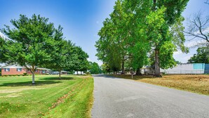 A residential street with houses, trees, and a clear sky.