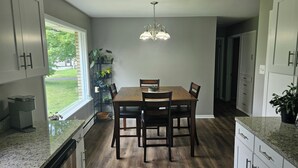 Een moderne keuken met een eettafel, stoelen en een kroonluchter.