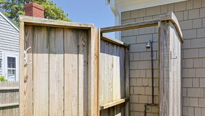 Un box de ducha exterior de madera con grifo metálico y manguera.
