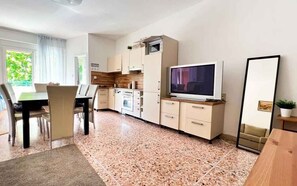 Une cuisine moderne équipée d’un téléviseur, de placards et d’un coin repas avec des chaises.
