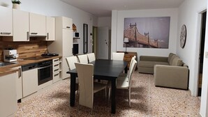 En kompakt opholdsstue med tekøkken, spiseplads og siddeområde.