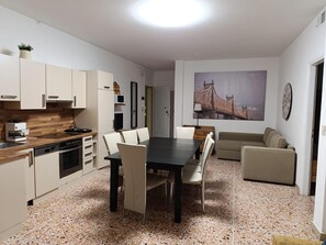 Un espace de vie compact comprenant un coin cuisine, un coin repas et un coin salon.