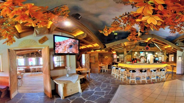 A rustic interior with a bar area, stone flooring, wooden beams, and autumn leaves. - Holiday House with Mountain View (Brixen im Thale)