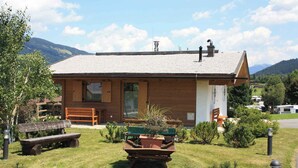 A wooden cabin with a sloped roof, a bench, a table with potted plants, and a view of the surrounding landscape. - Holiday House with Mountain View (Brixen im Thale)