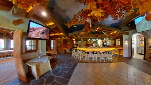 A rustic interior with a stone floor, wooden furniture, a bar area, and a television mounted on the wall. - Holiday House with Mountain View (Brixen im Thale)