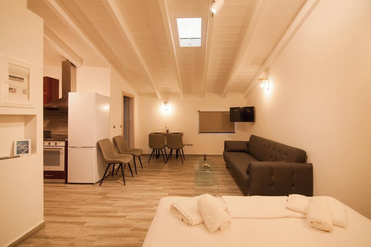 Une chambre d’hôtel compacte comprenant un coin cuisine, un canapé, un espace repas et un lit.