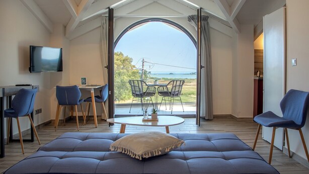 Un salon moderne avec un grand canapé, une table à manger et des chaises, ainsi qu’un téléviseur fixé au mur.