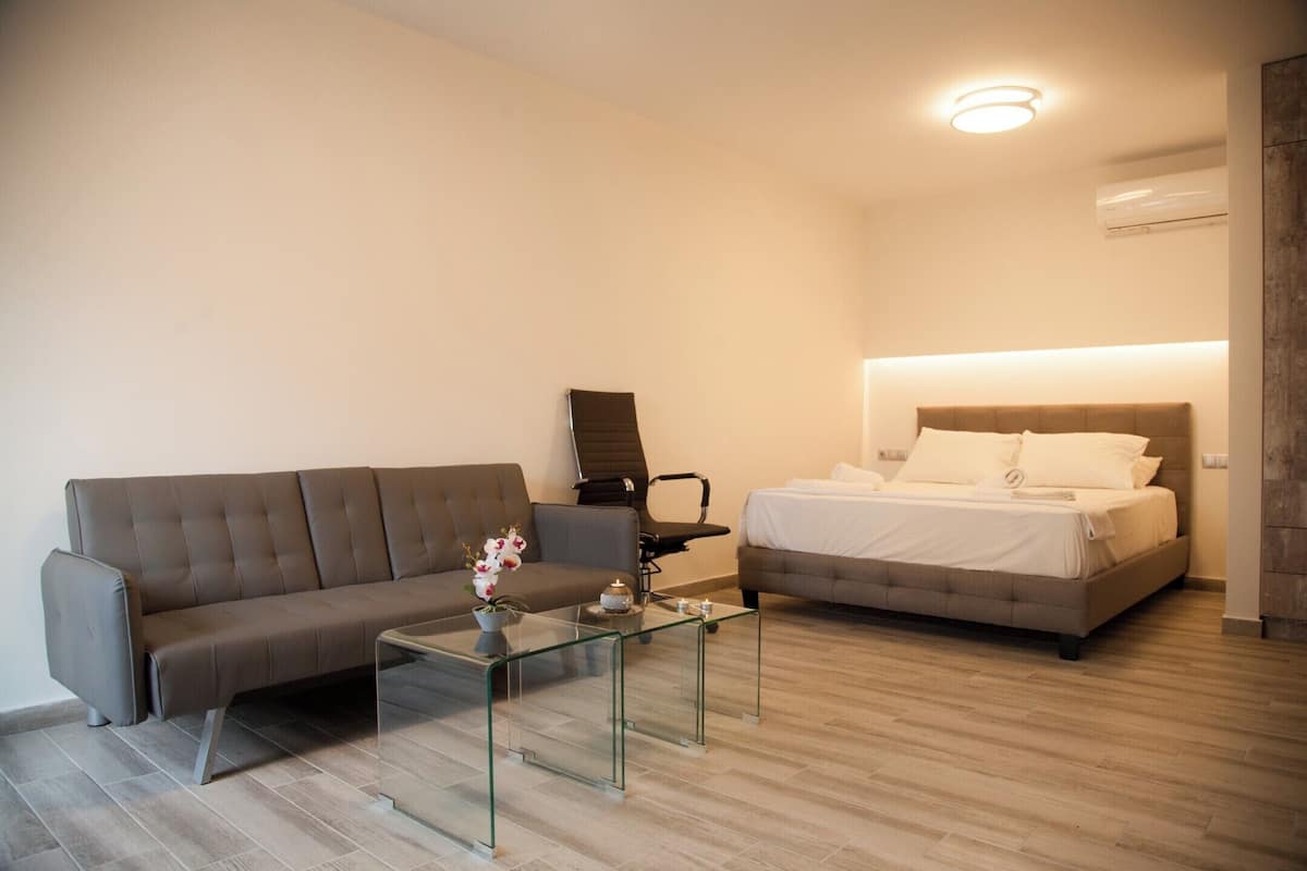 Une chambre d’hôtel moderne équipée d’un canapé, d’une table basse en verre, d’un lit et d’un bureau.