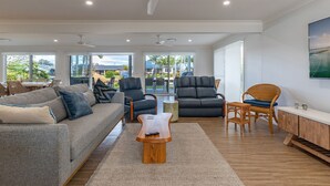 A spacious living room with a grey sofa, black leather chairs, a wooden coffee table, and a wicker chair. - 37 Victor Avenue on the Forster Keys (Forster)