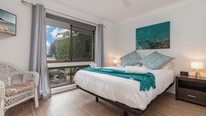A bedroom with a bed, two bedside tables, a chair, a window with curtains, and a painting on the wall. - 37 Victor Avenue on the Forster Keys (Forster)