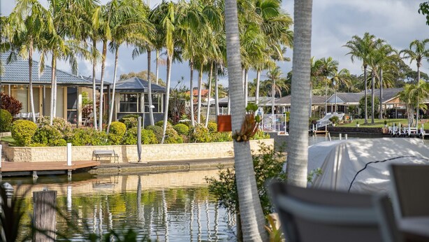 A resort with a pool, palm trees, and houses in the background. - 37 Victor Avenue on the Forster Keys (Forster)