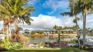 A lakeside view with palm trees, a dock, and a building with a sloped roof. - 37 Victor Avenue on the Forster Keys (Forster)