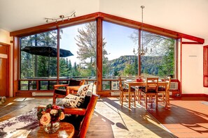 Un'ampia stanza con grandi finestre, un pontile in legno e un'area pranzo.
