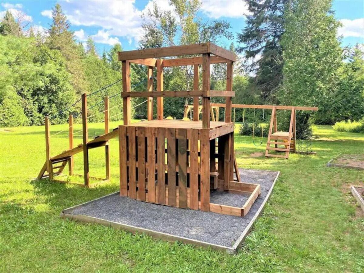 Una estructura de juego de madera en un área exterior con césped.