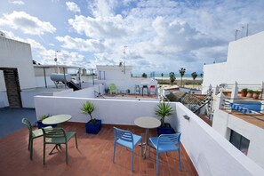 Una terraza en la azotea con asientos al aire libre, plantas en macetas y vistas a la playa.