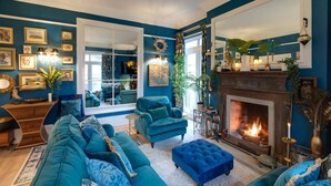 Un salon aux murs de couleur turquoise, doté d’une cheminée et d’une grande fenêtre.