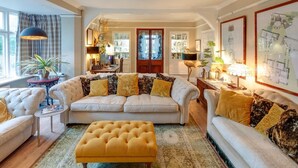 Un salon spacieux comprenant un grand canapé, un pouf jaune et un coin repas avec une table et des chaises.