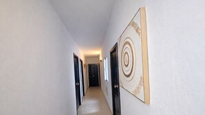 A hallway with doors, a light fixture, and a decorative wall piece.
