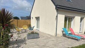 A house with a patio area featuring outdoor furniture and a planter. - Au délices d'Anne Laure !   (Pleumeur-Gautier)