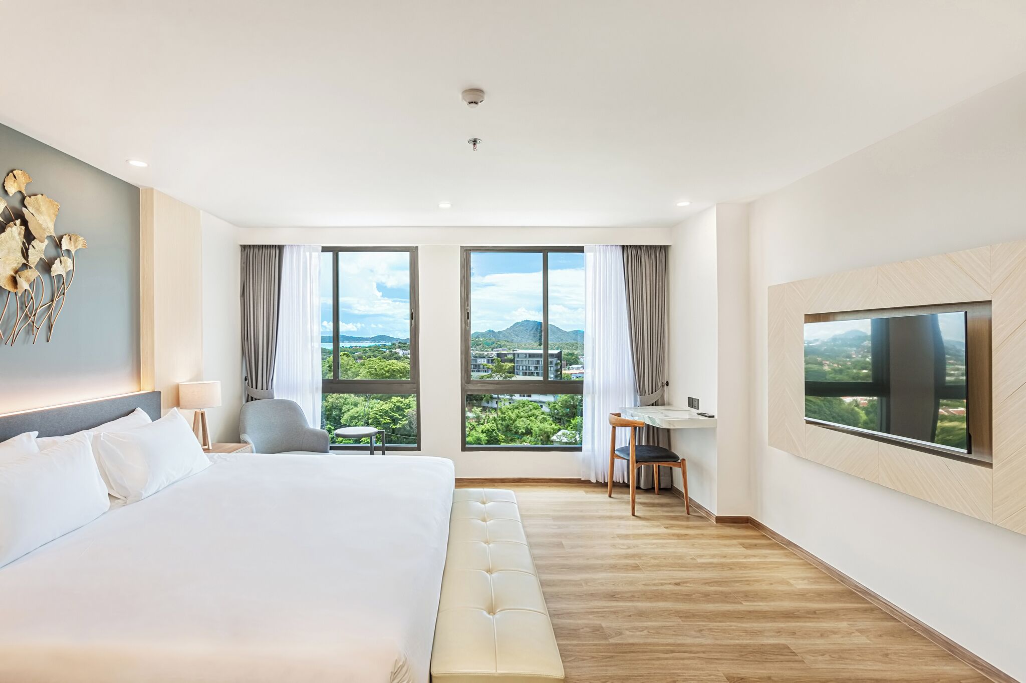 A modern hotel room with a large bed, a desk, and a TV.