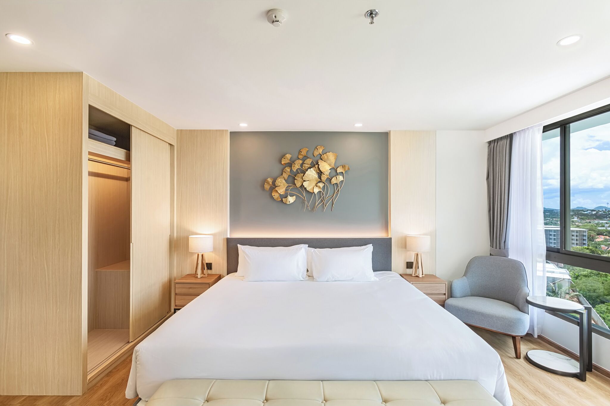 A modern hotel room with a large bed, a seating area, and a view of the city.