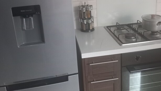 Una cucina con frigorifero in acciaio inox, dispenser per acqua, piano cottura a gas e forno a microonde.