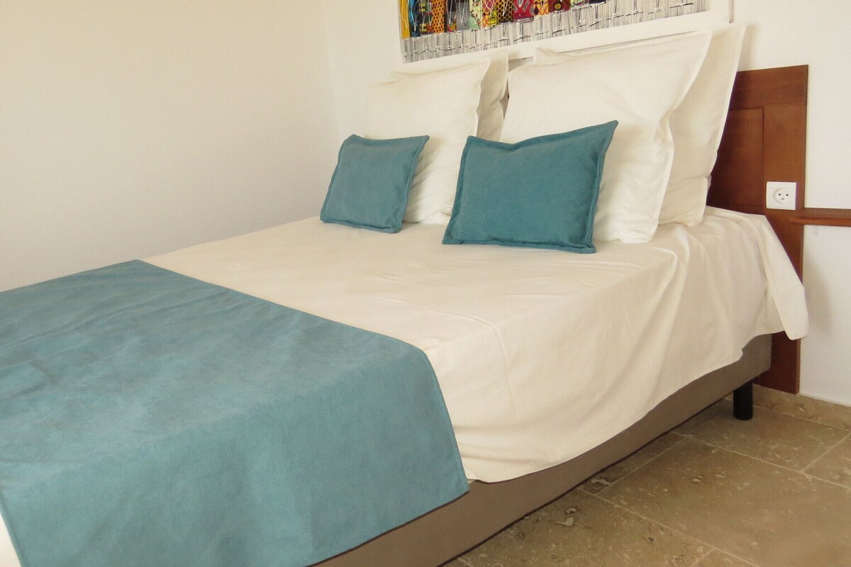 A bed with a white mattress and teal bedding, including a blanket and pillows.