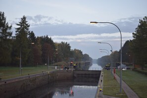 Ein Kanal mit einer Schleusenanlage, umgeben von Bäumen und einer Grünfläche mit Straßenlaternen.