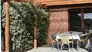 A patio with a table and chairs, a brick wall, and a wooden pergola. - Pension zur Schleuse (Witzeeze)