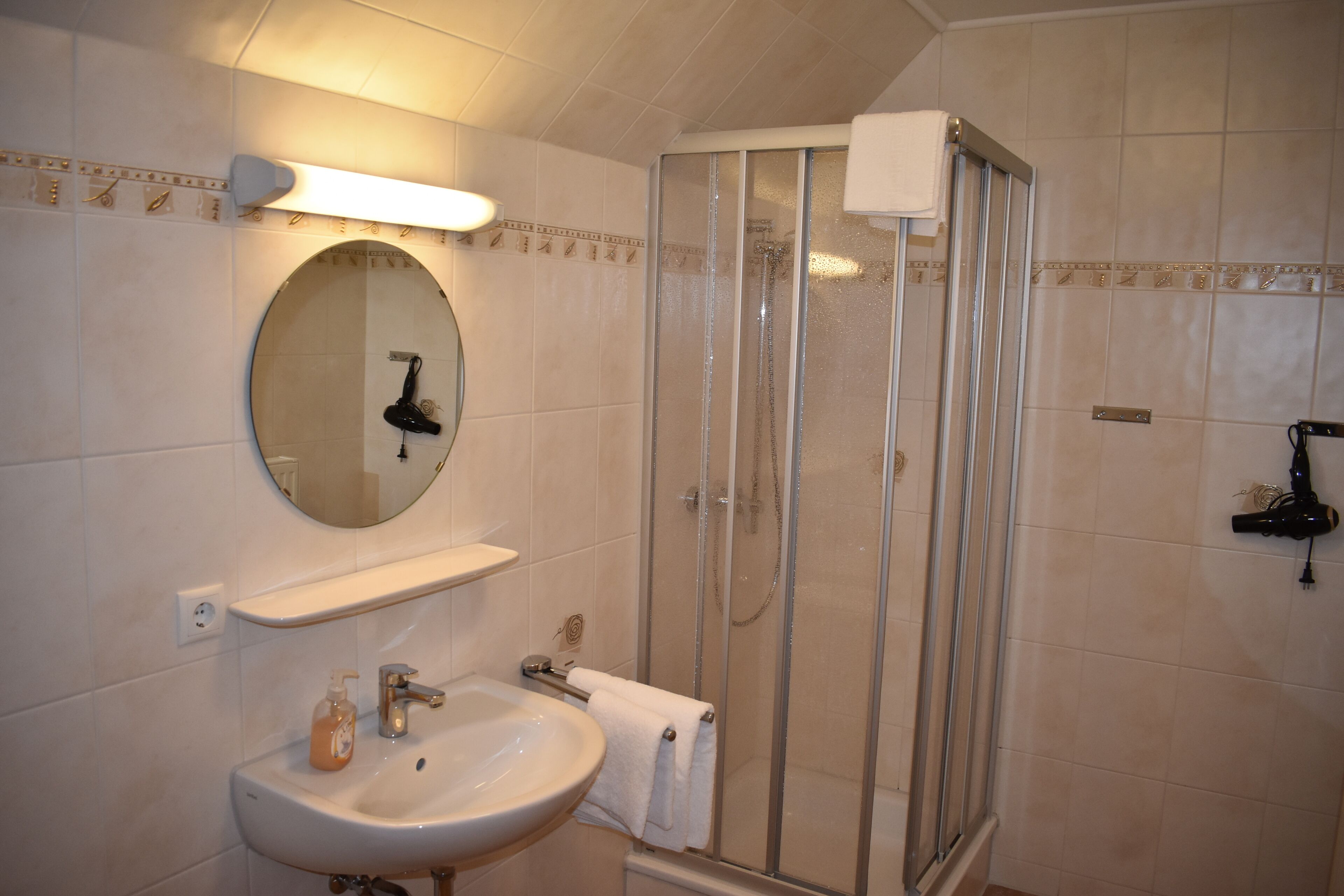 A bathroom with a sink, mirror, and shower.