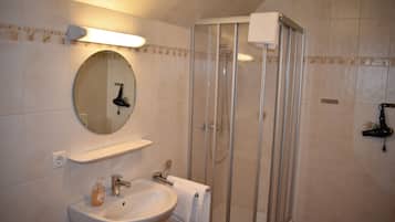 A bathroom with a sink, mirror, and shower.