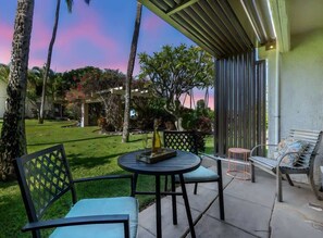 Une terrasse extérieure avec une table ronde et des chaises, un banc et une pergola.