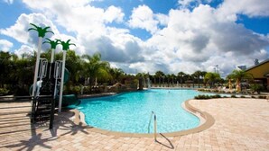 A swimming pool with a curved edge, palm trees, and a clear sky.